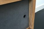 TV meubel van eiken aan de wand met zwart mdf deurtjes detail deur